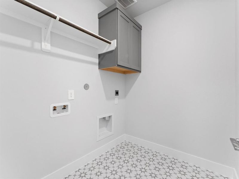 Utility Room with Patterned Tile Flooring, Washer and Dryer Connections, Storage Cabinet, and Hanging Bar.