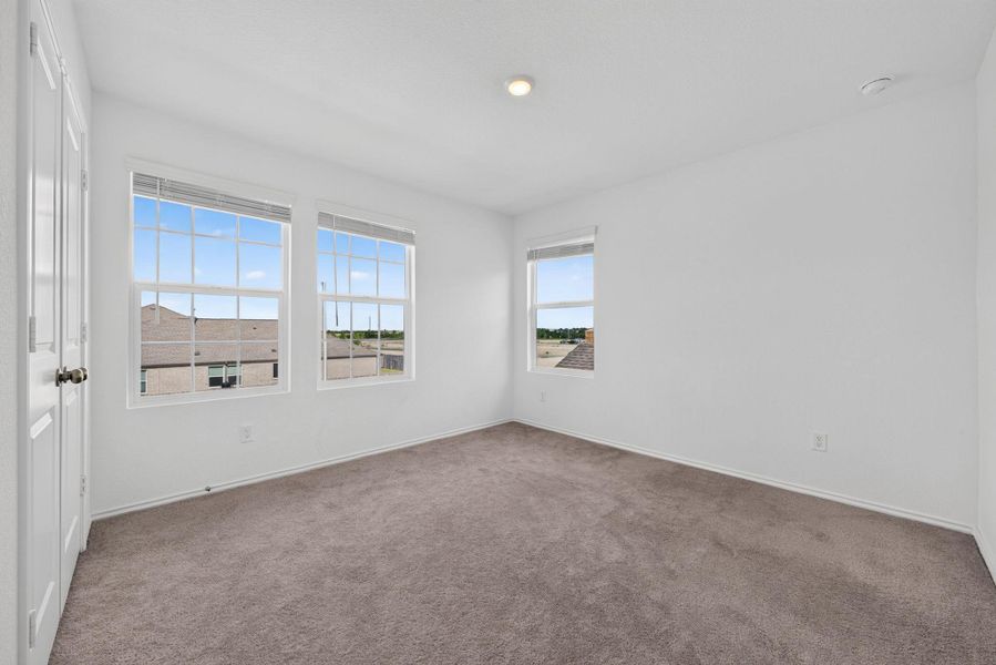 A well-lit room offers neutral carpeting and multiple windows. A well-lit room offers neutral carpeting and multiple windows.