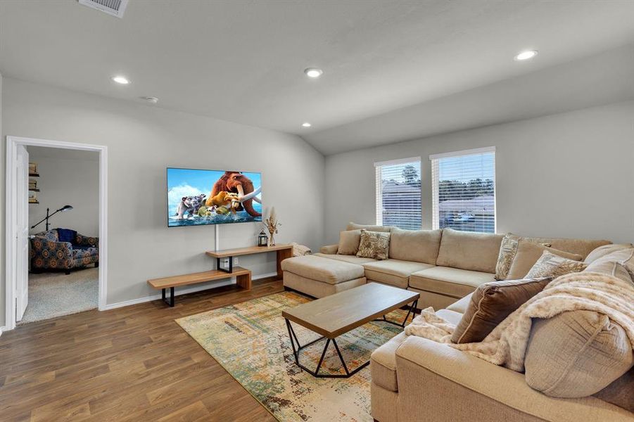 Inviting living area with double windows that fill the space with natural light. Ample seating makes it an ideal spot for cozy movie nights or gathering with friends for football games.