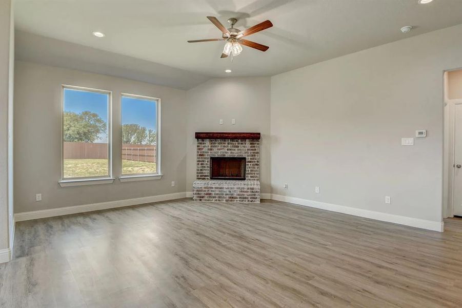 Unfurnished living room with ceiling fan, wood finished floors, baseboards, recessed lighting, and a fireplace
