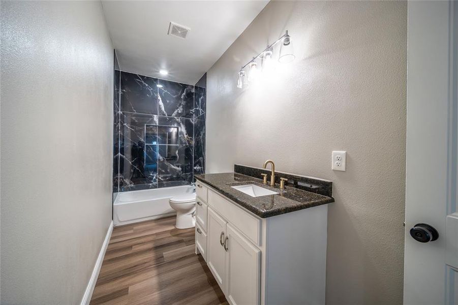 Full bathroom featuring toilet, bathtub / shower combination, hardwood / wood-style flooring, and vanity