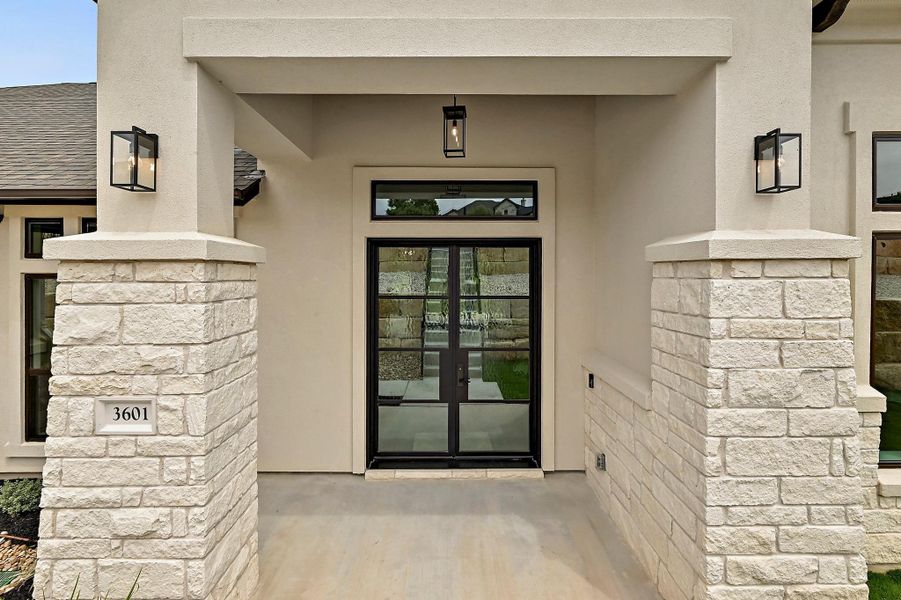 A welcoming entry featuring a stucco exterior with stone accents and a prominent double door.