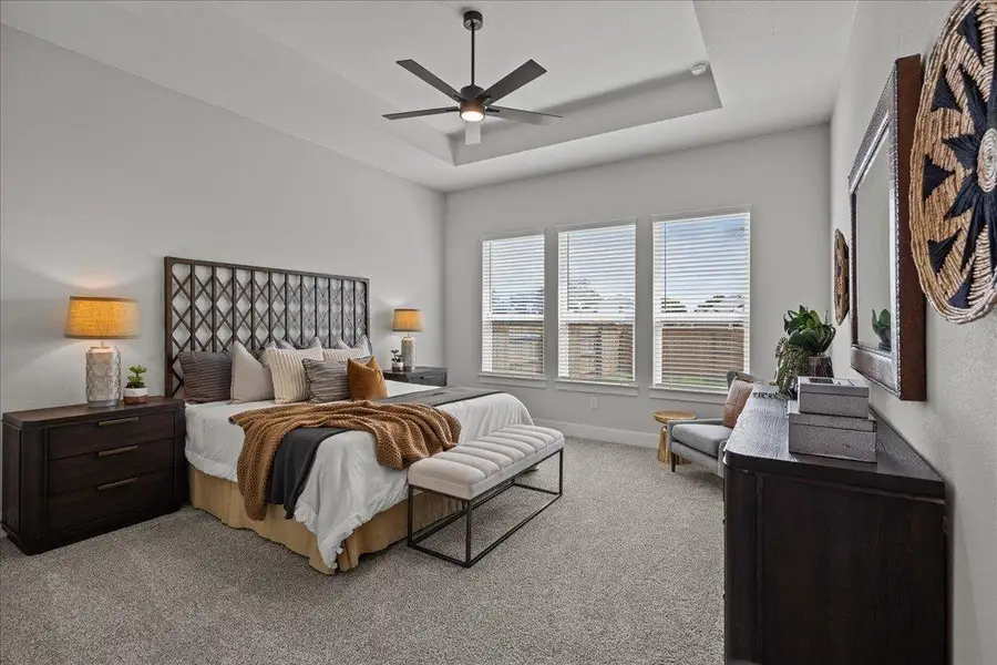 Bedroom with light carpet, a tray ceiling, baseboards, and ceiling fan Bedroom with light carpet, a tray ceiling, baseboards, and ceiling fan