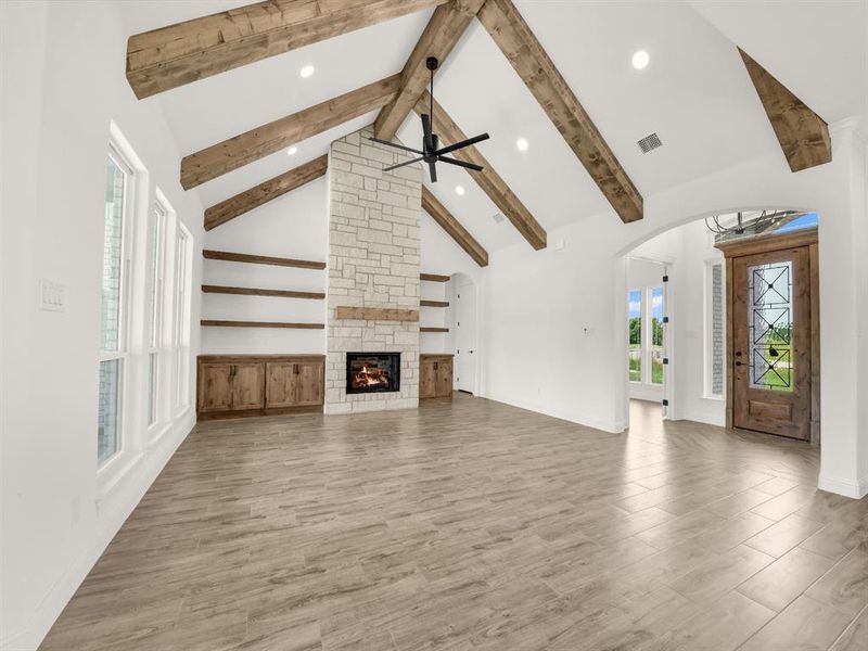 Unfurnished living room with beamed ceiling, wood finished floors, recessed lighting, plenty of natural light, and arched walkways Unfurnished living room with beamed ceiling, wood finished floors, recessed lighting, plenty of natural light, and arched walkways