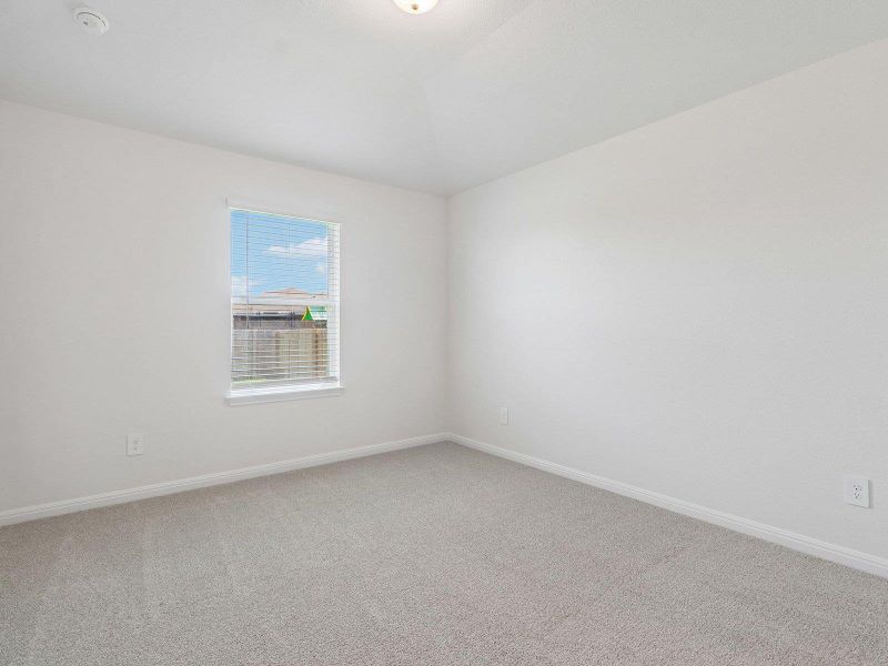 Soft carpeting pairs with neutral walls and a window overlooking the backyard.