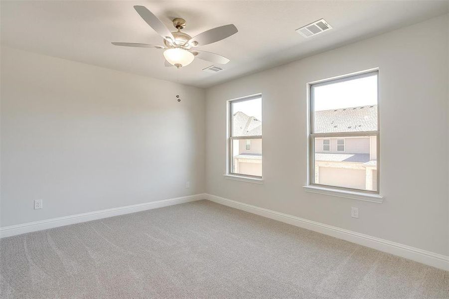 Unfurnished room featuring light carpet and a ceiling fan Unfurnished room featuring light carpet and a ceiling fan