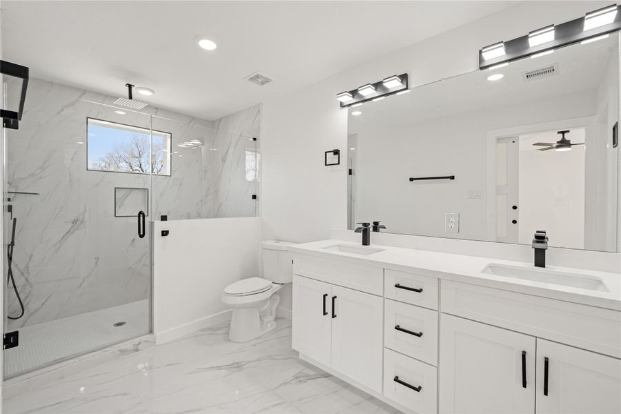 Primary bath showcasing a double vanity with ample storage, contemporary lighting, and convenient access to the walk-in closet for added functionality. Primary bath showcasing a double vanity with ample storage, contemporary lighting, and convenient access to the walk-in closet for added functionality.