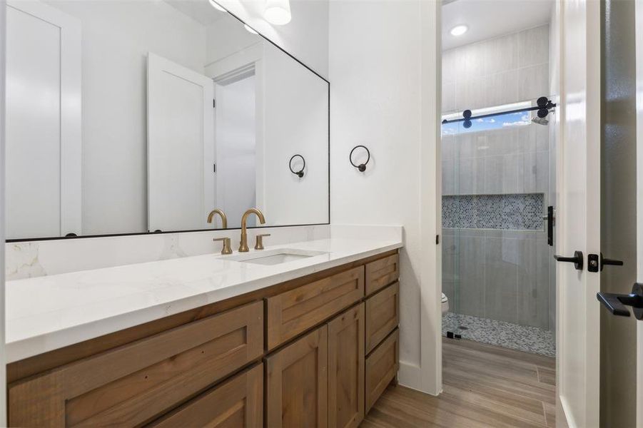 Bathroom featuring a shower with shower door, vanity, and toilet