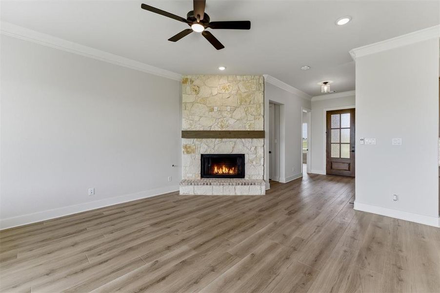 Living area featuring a stone fireplace with a wood mantel, wood-finish flooring, recessed lighting, and a ceiling fan