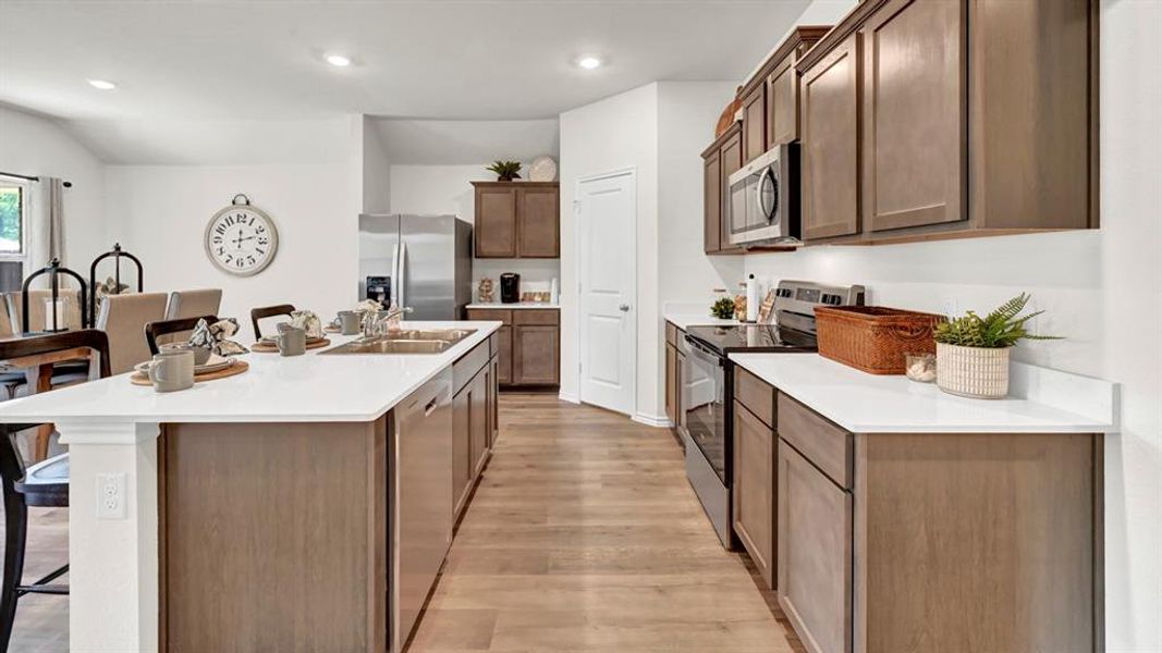 Kitchen featuring a breakfast bar area, stainless steel appliances, a center island with sink, light wood-type flooring, and recessed lighting