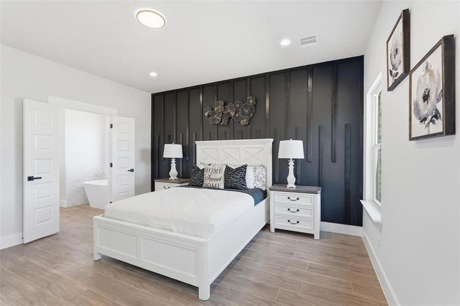 Bedroom with wood tiled floors, ensuite bath, and recessed lighting