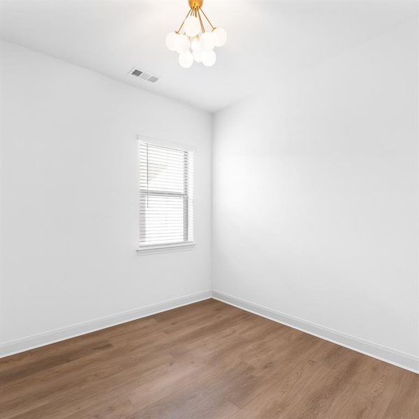 Empty room with wood finished floors and a chandelier Empty room with wood finished floors and a chandelier