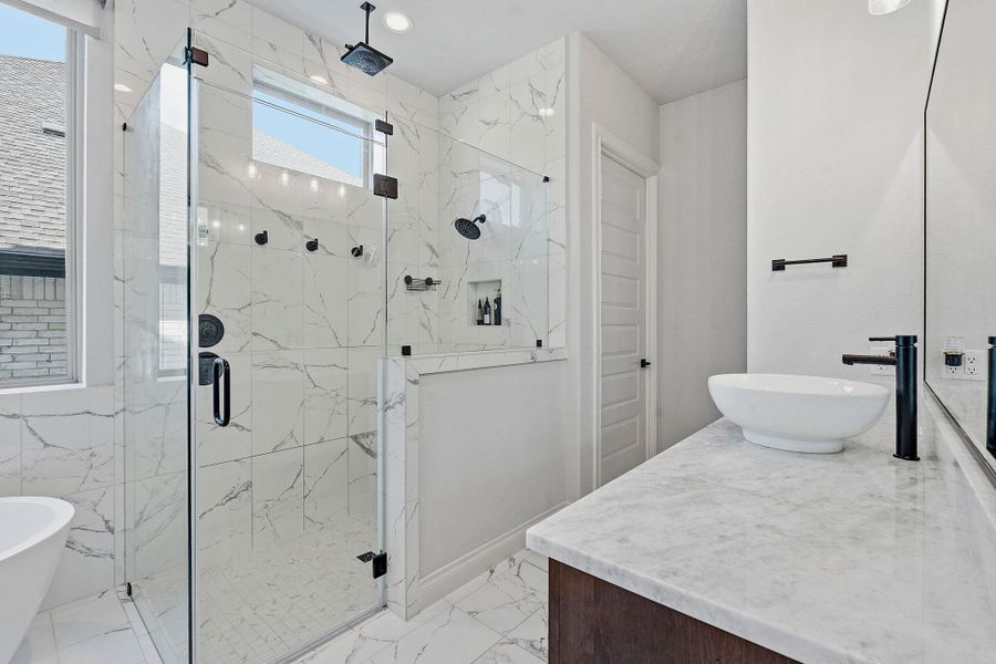Marble-clad bathroom features a spacious glass-enclosed shower and a sleek vessel sink. Marble-clad bathroom features a spacious glass-enclosed shower and a sleek vessel sink.