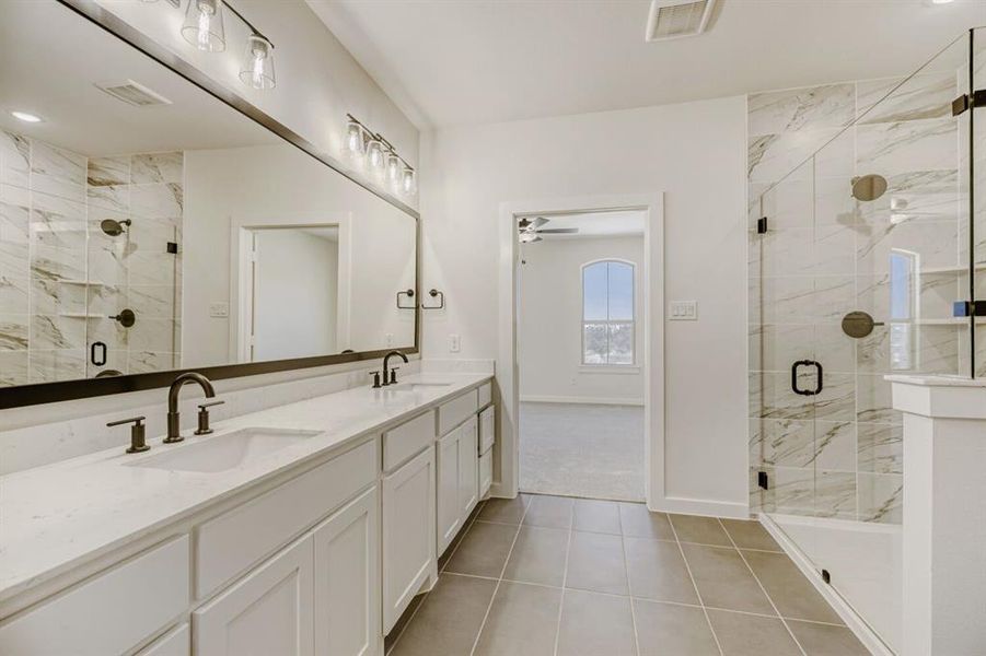 Bathroom with double vanity, a marble finish shower, light tile patterned flooring, and a ceiling fan