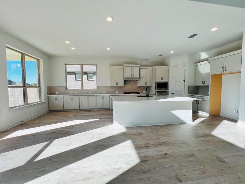 Kitchen featuring backsplash, recessed lighting, a kitchen island with sink, light wood-style flooring, and stainless steel appliances