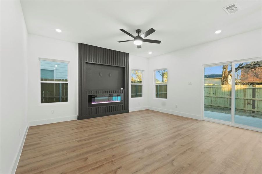 Unfurnished living room featuring a ceiling fan, light wood finished floors, a fireplace, and recessed lighting