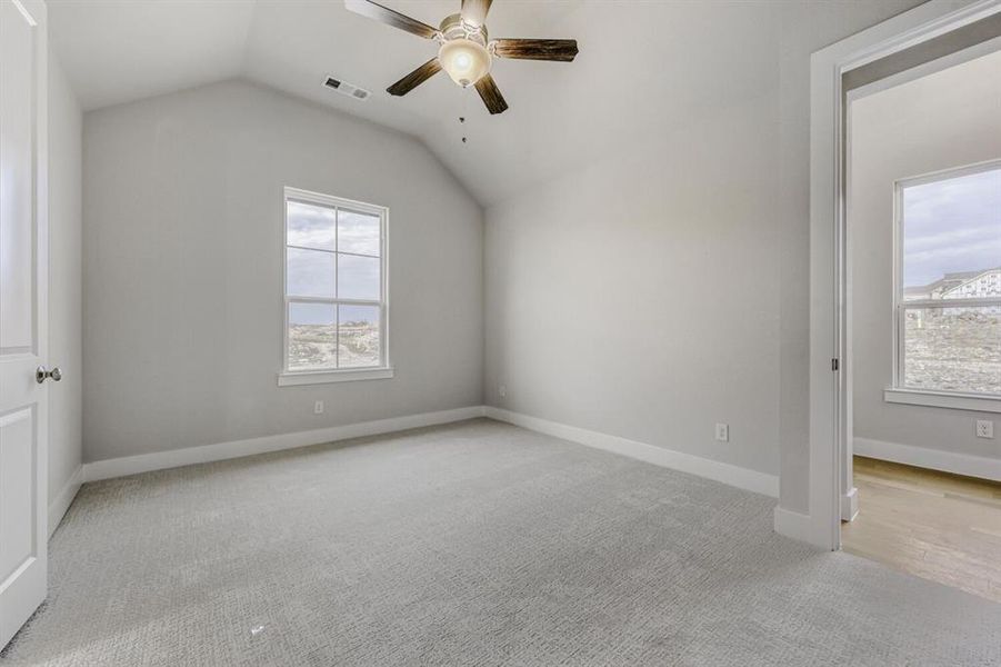 Additional living space featuring light carpet and ceiling fan