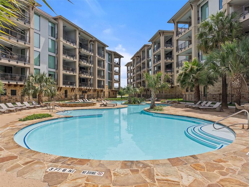 Expansive resort-style swimming pool featuring a curved design and integrated steps, surrounded by flagstone paving Expansive resort-style swimming pool featuring a curved design and integrated steps, surrounded by flagstone paving