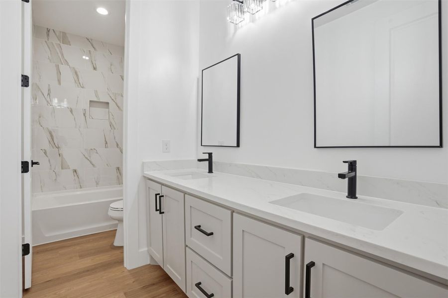 Full bath featuring double vanity, light wood-style flooring, shower / tub combination, and recessed lighting