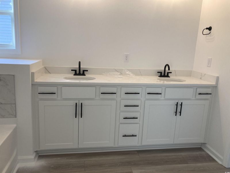 Bathroom with double vanity, light wood-style flooring, and a tub Bathroom with double vanity, light wood-style flooring, and a tub