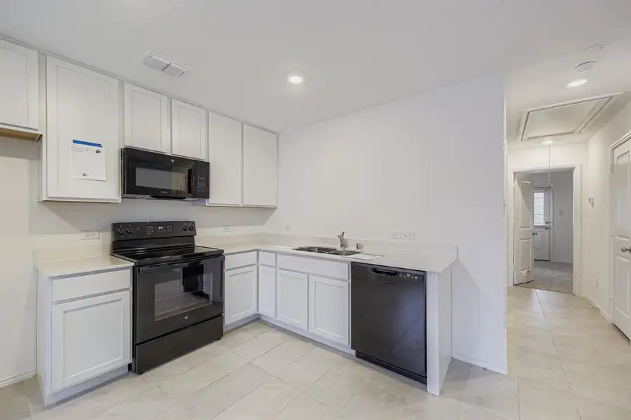 Kitchen featuring light countertops, white cabinets, black appliances, recessed lighting, and open floor plan