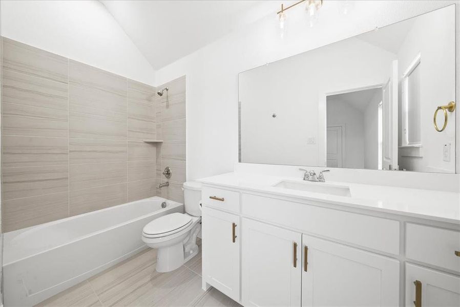 Bathroom featuring lofted ceiling, shower / bath combination, toilet, vanity, and tile patterned flooring