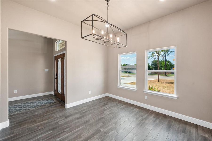 Dining room featuring chandelier, and Wood-finish tile flooring. View facing the entryway with inset mosaic tile pattern