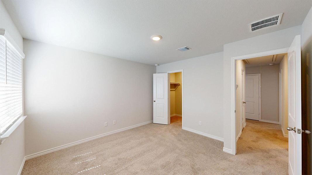 Spacious room featuring carpeted flooring, a window with blinds, and a built-in closet with shelving