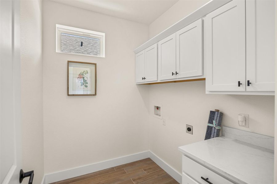 Functional laundry room featuring built-in cabinetry, a convenient countertop, and ample utility hookups.