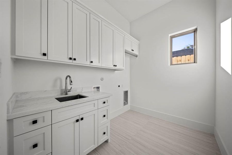 This well-appointed mudroom offers convenience and functionality with ample cabinetry for storage and a built-in sink for easy clean-ups. The bright window fills the space with natural light, while the durable countertop and elegant design make it both practical and stylish. Perfectly situated for household organization, this space is designed to meet everyday needs with ease and sophistication