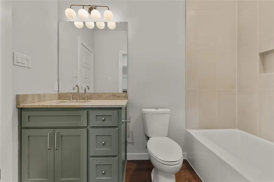 Full bath featuring vanity, dark wood-style floors, and shower combination Full bath featuring vanity, dark wood-style floors, and shower combination