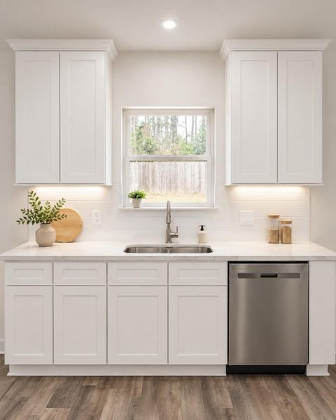 Bright and modern kitchen featuring a stainless-steel dishwasher, and a large window for natural light.