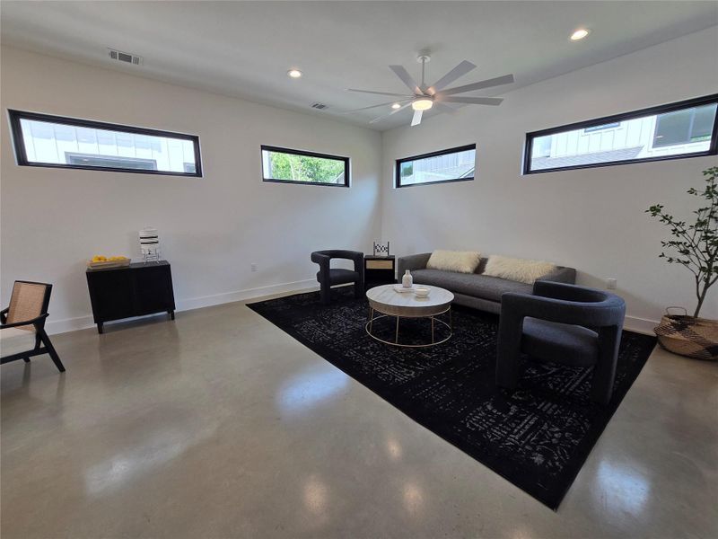 Living room featuring recessed lighting, visible vents, baseboards, and finished concrete floors Living room featuring recessed lighting, visible vents, baseboards, and finished concrete floors