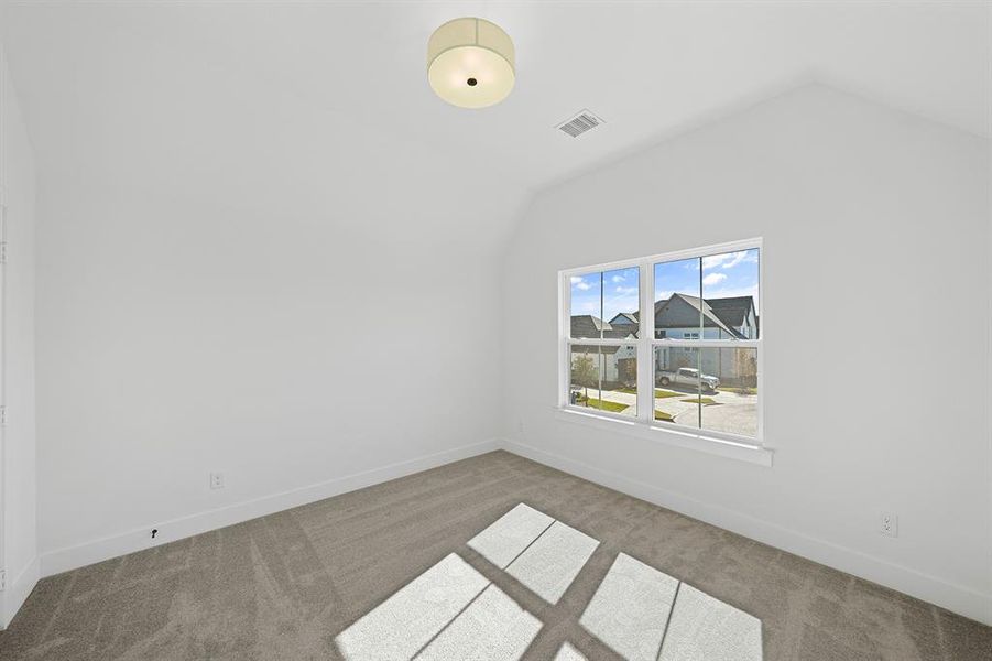 Carpeted spare room featuring lofted ceiling and baseboards Carpeted spare room featuring lofted ceiling and baseboards