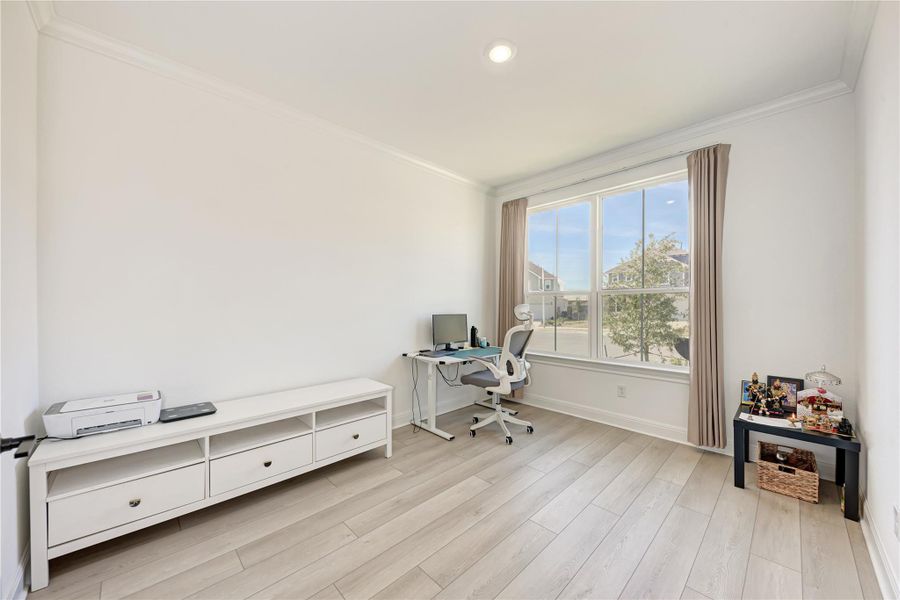 Spacious room featuring light wood-finish flooring, ample natural light from a large picture window, recessed lighting, and crown molding