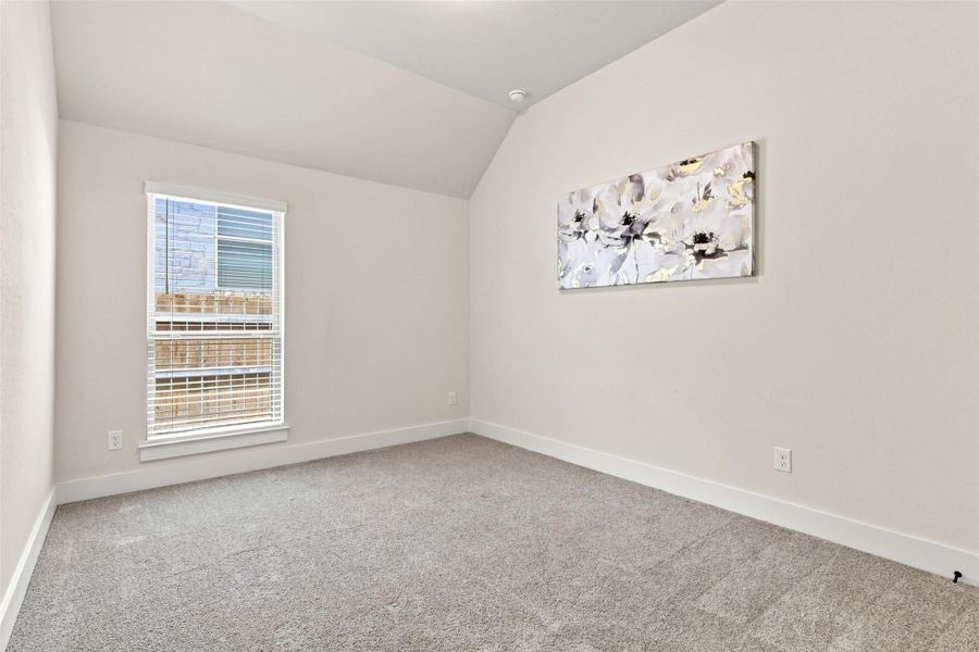 A window-filled room with vaulted ceilings offers a versatile space for rest or productivity.