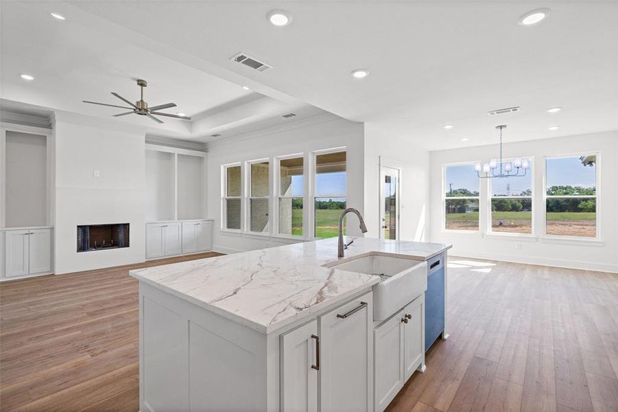 Kitchen island with a farmhouse sink and pull-down faucet, featuring a light-toned countertop with veining