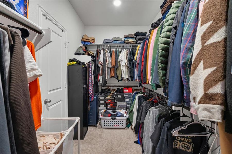 Walk-in closet featuring carpet flooring and multiple clothing rods
