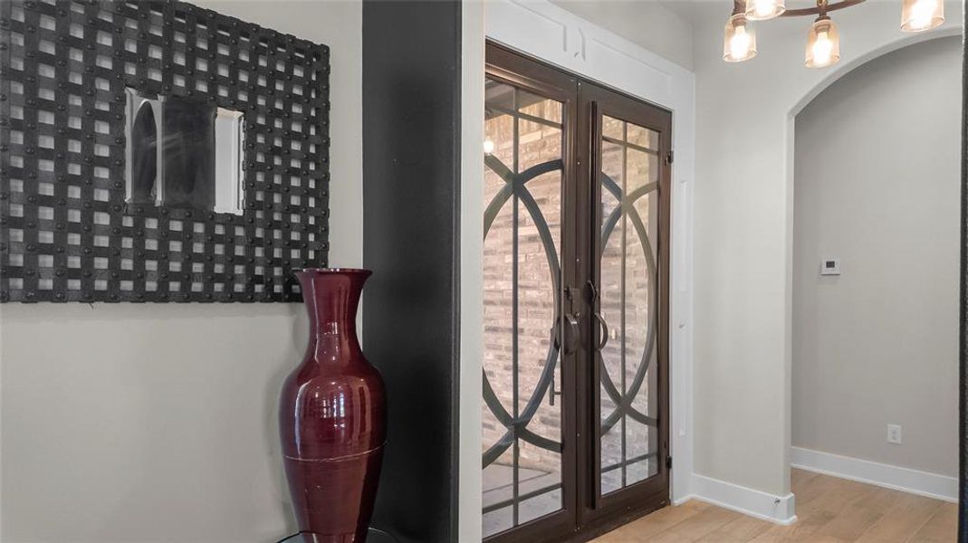 Foyer with light wood-style floors, french doors, and arched walkways