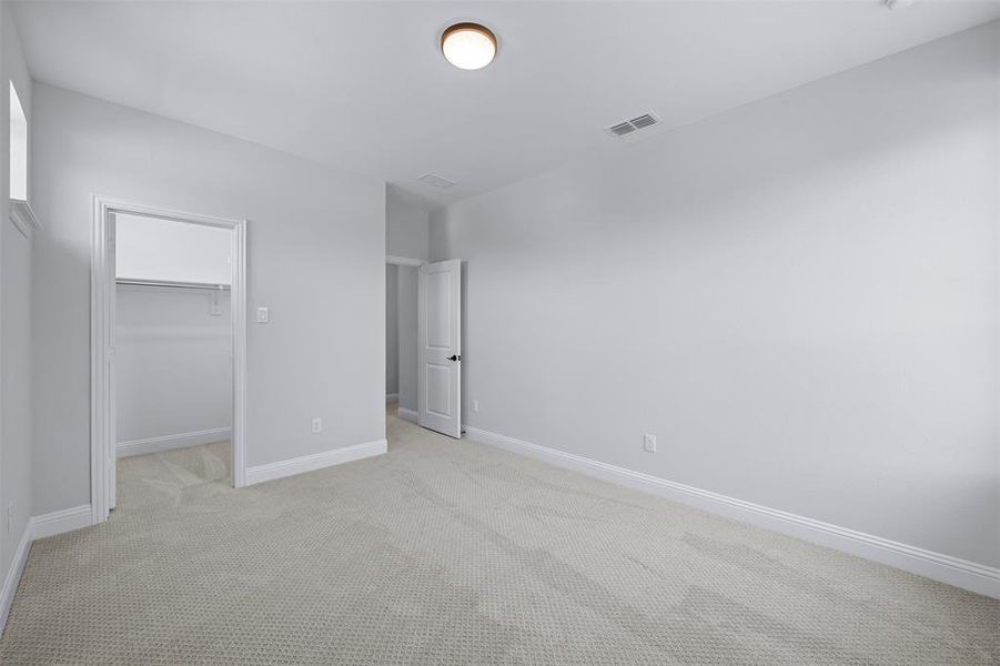 Unfurnished bedroom featuring light colored carpet and a spacious closet