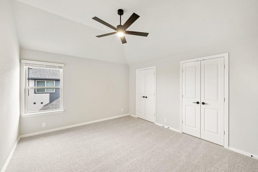 Empty bedroom with carpet, ceiling fan, two closets, and a window Empty bedroom with carpet, ceiling fan, two closets, and a window