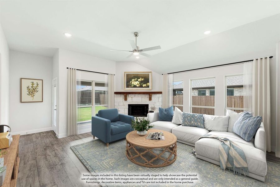 Living room with stone fireplace, vaulted ceiling, ceiling fan, and hardwood floors with large windows Living room with stone fireplace, vaulted ceiling, ceiling fan, and hardwood floors with large windows