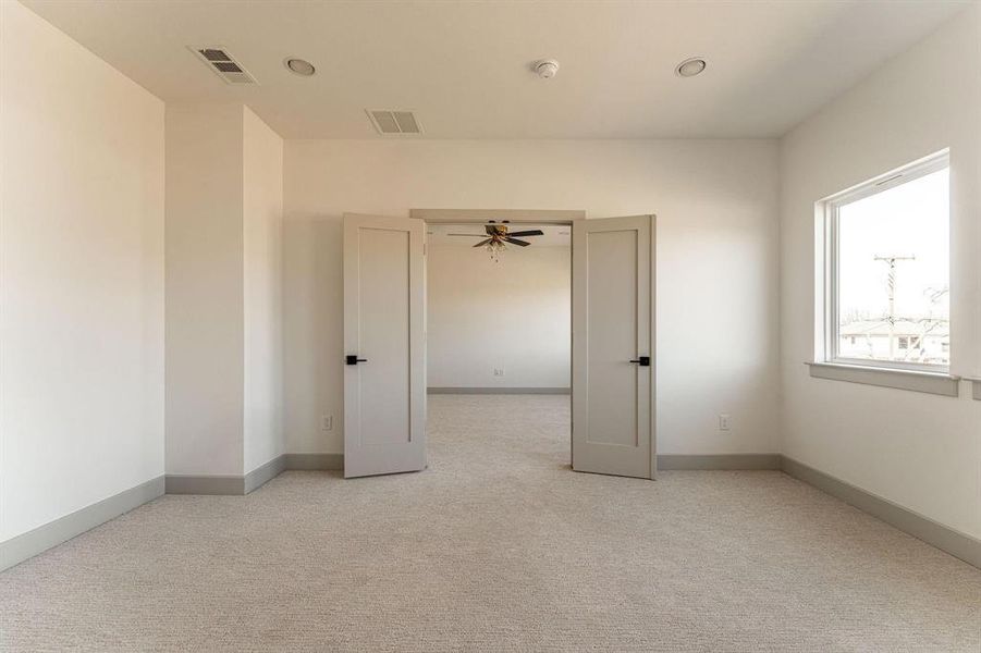Empty room featuring light colored carpet and ceiling fan