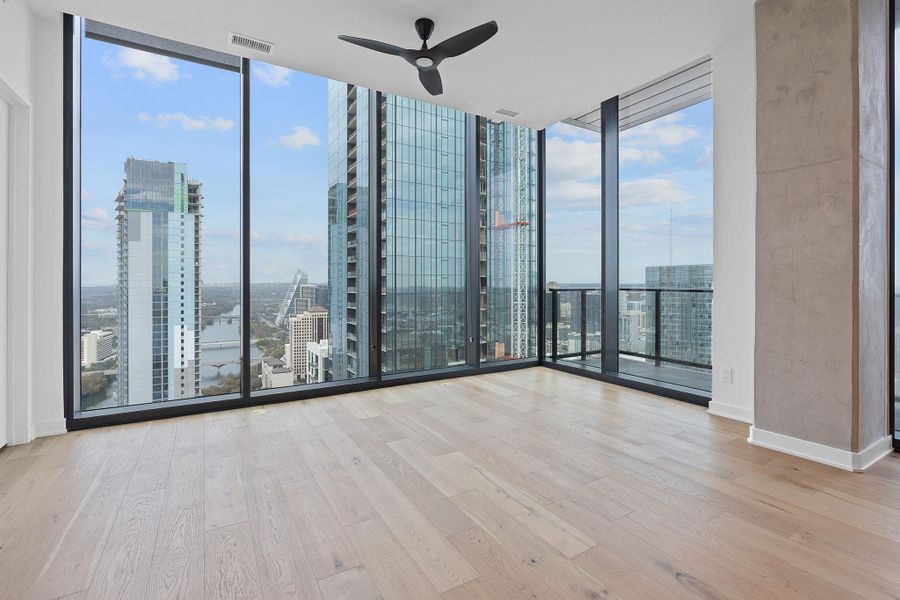 Room with expansive windows, a view of city, light wood-type flooring, and ceiling fan