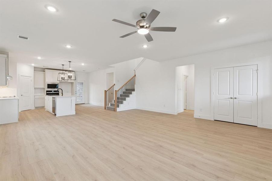 Unfurnished living room featuring a ceiling fan, stairs, recessed lighting, and light wood-style floors Unfurnished living room featuring a ceiling fan, stairs, recessed lighting, and light wood-style floors