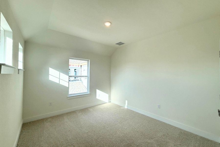 A well-lit bedroom with soft carpeting and natural light streaming through two windows. A well-lit bedroom with soft carpeting and natural light streaming through two windows.