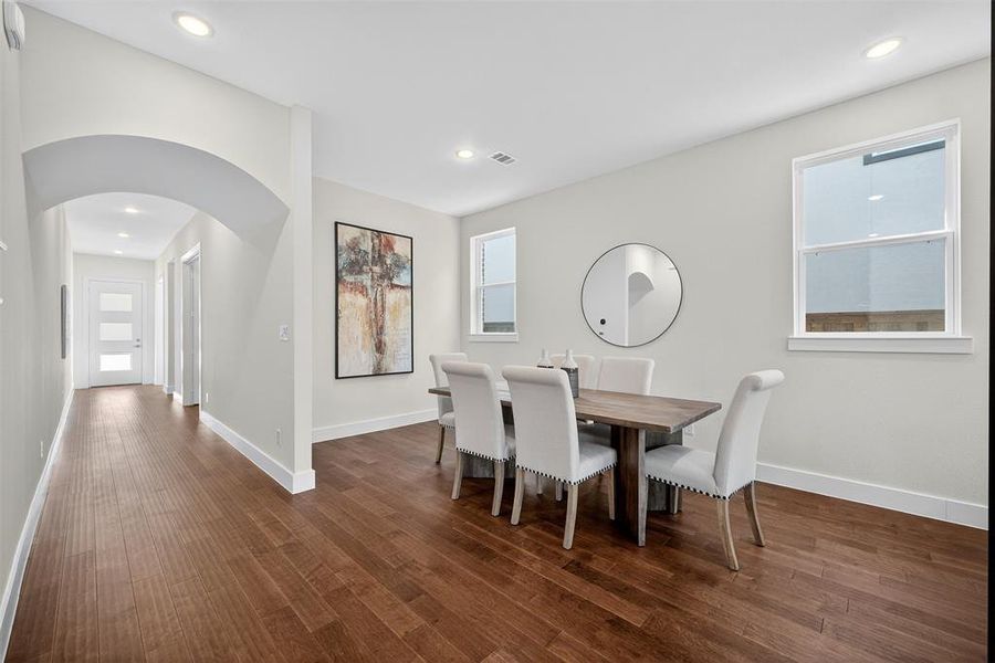 Dining area featuring arched walkways, healthy amount of natural light, recessed lighting, and dark wood-type flooring