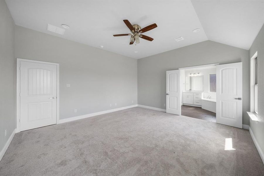 Unfurnished bedroom featuring ensuite bath, carpet, ceiling fan, and lofted ceiling