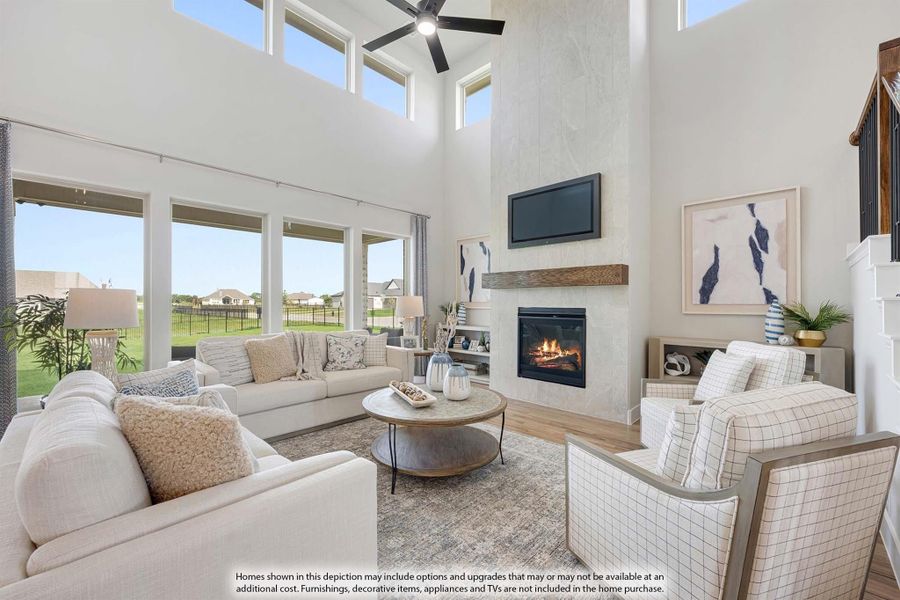 Living room with two-story ceiling, stone fireplace, ceiling fan, and large windows with backyard views