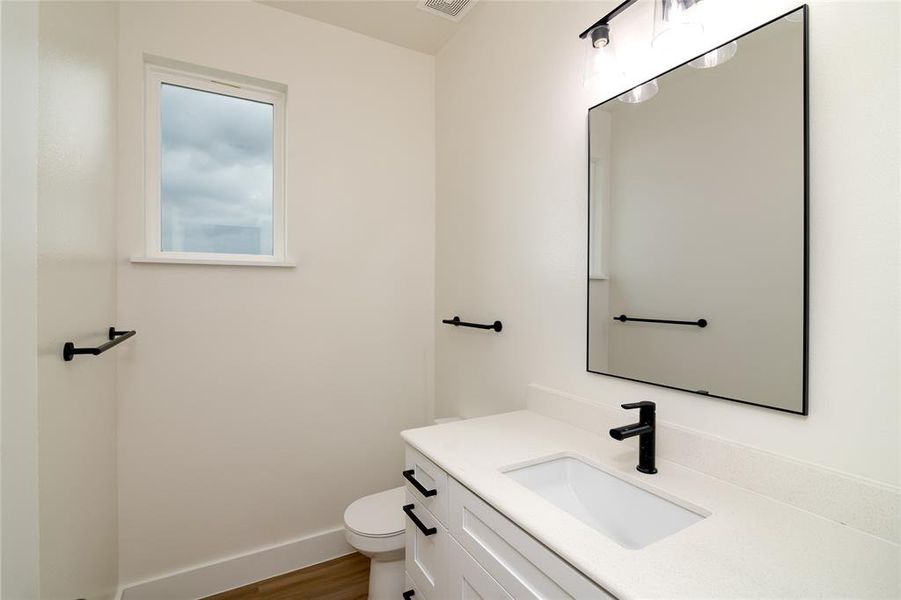 Bathroom with hardwood / wood-style floors, vanity, and toilet